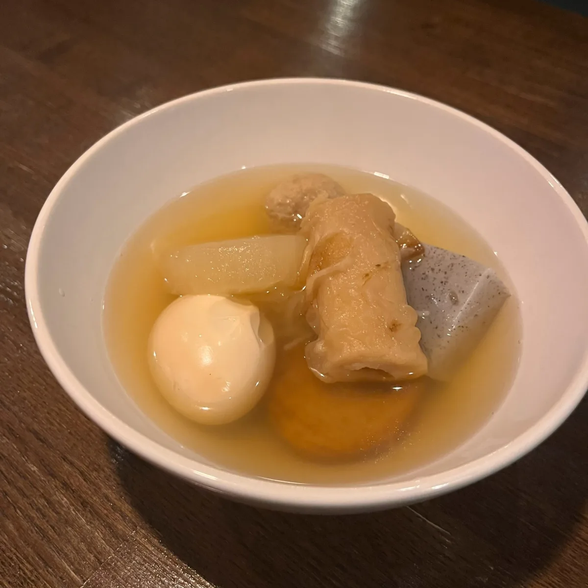 白い器に盛られたおでん。大根や卵、ちくわぶなどの具材が出汁に入っている。